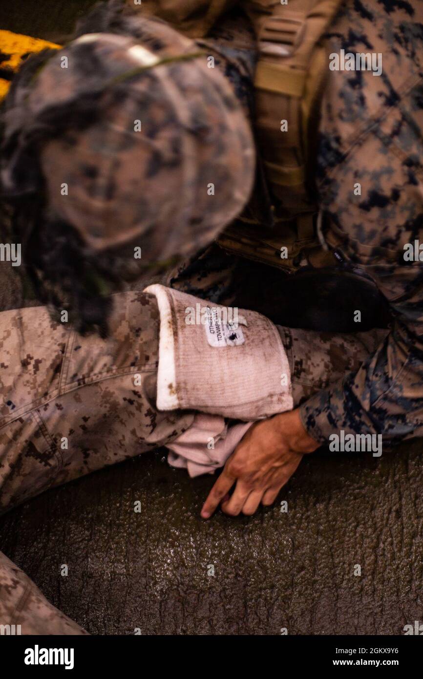 Una medicazione a pressione è applicata alla gamba di un incidente di addestramento durante l'applicazione pratica finale di una classe di salvavita di combattimento (CLS) a bordo della USS Germantown (LSD 42) nel Mare dei Coralli, 16 luglio 2021. La 31esima unità Marine Expeditionary Unit (MEU) opera a bordo di navi del gruppo Americ Expeditionary Strike Group nell'area operativa della settima flotta per migliorare l'interoperabilità con alleati e partner e servire come forza di reazione pronta a difendere la pace e la stabilità nella regione IndoPacifico. Foto Stock