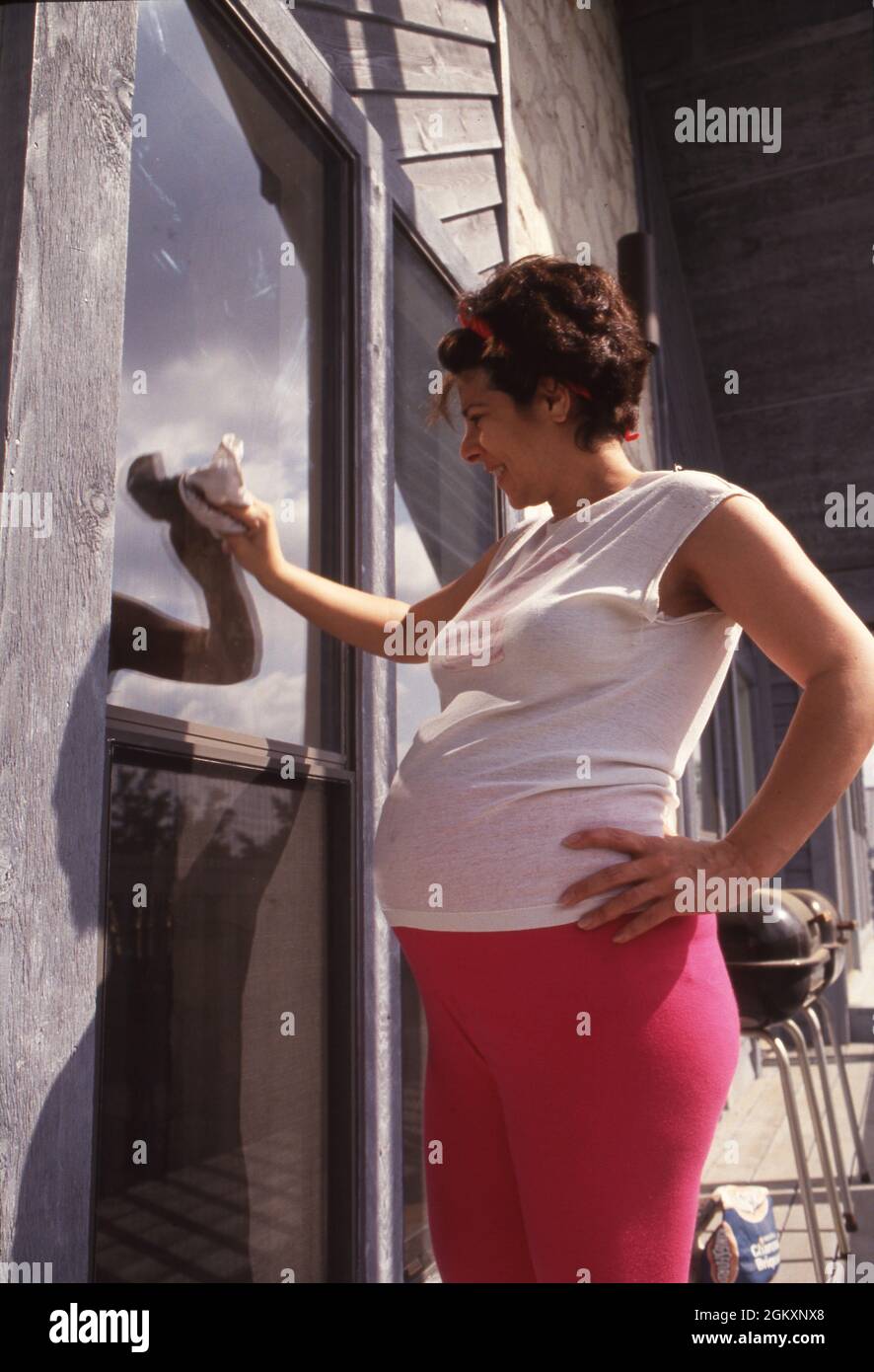 ©1994 donna incinta lava le finestre a casa, otto mesi incinta. Foto Stock