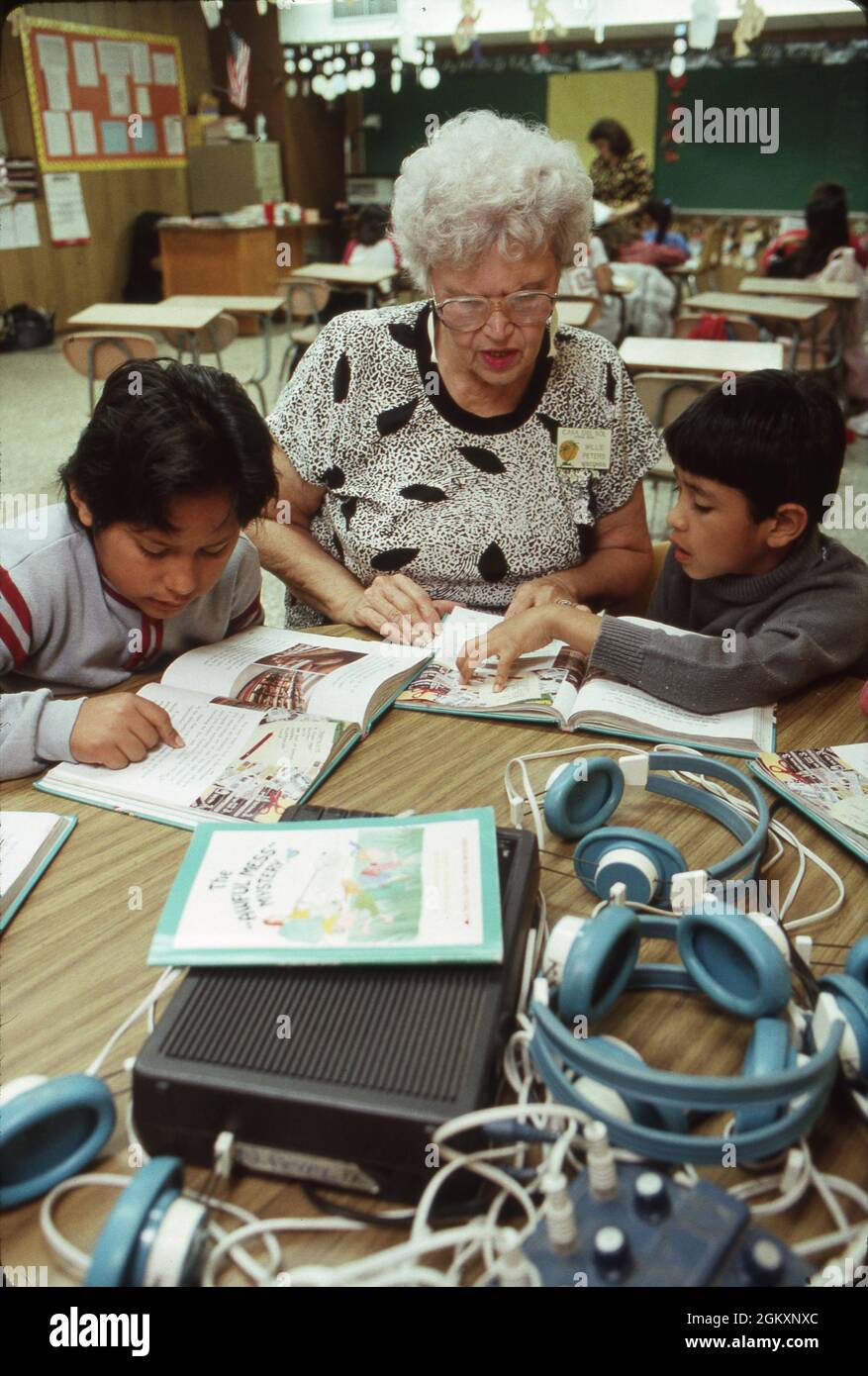 ©1990 insegnante volontario in pensione che lavora alla lettura con bambini ispanici che imparano lentamente. SIGNOR Foto Stock
