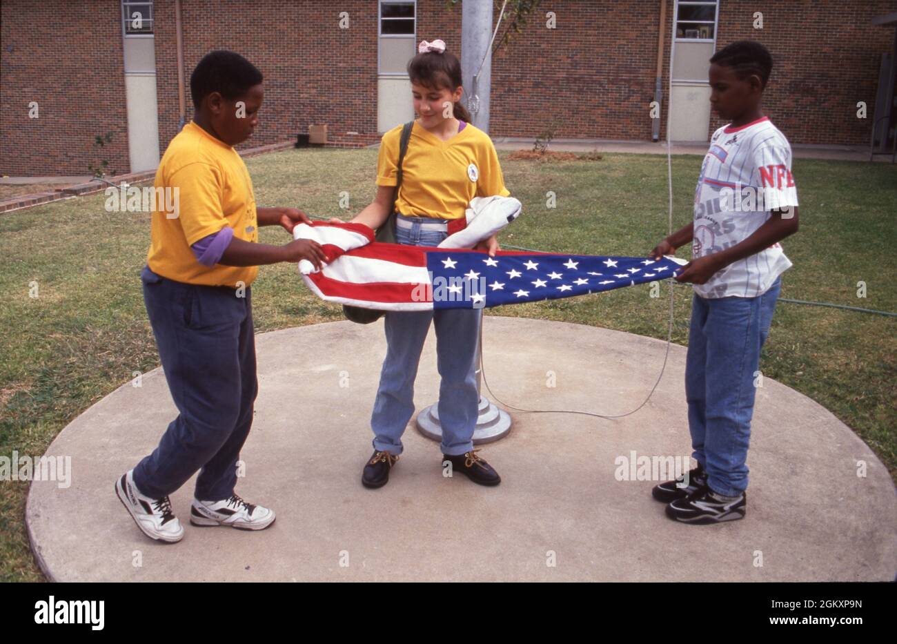 ©1992 studenti giovani in alto piegano la bandiera a fine giornata, Webb Junior High, Austin Foto Stock