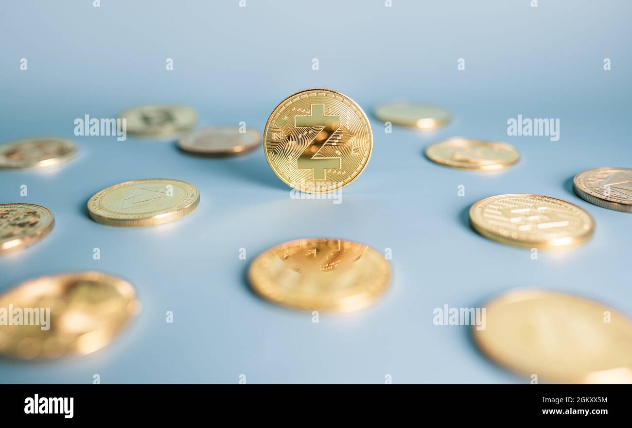 Moneta Zcash in piedi in posizione centrale tra mazzo di cripto monete su sfondo blu. Primo piano, messa a fuoco morbida. Banner con token Zec dorato. Foto Stock