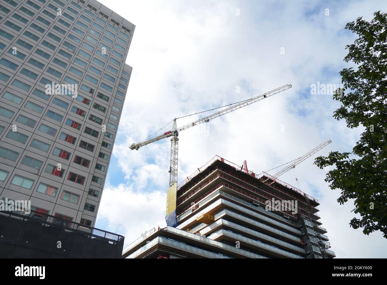 Cantiere di costruzione aziendale con gru a Rotterdam. Accanto c'è un altro edificio aziendale. Vista ad angolo basso. Foto Stock