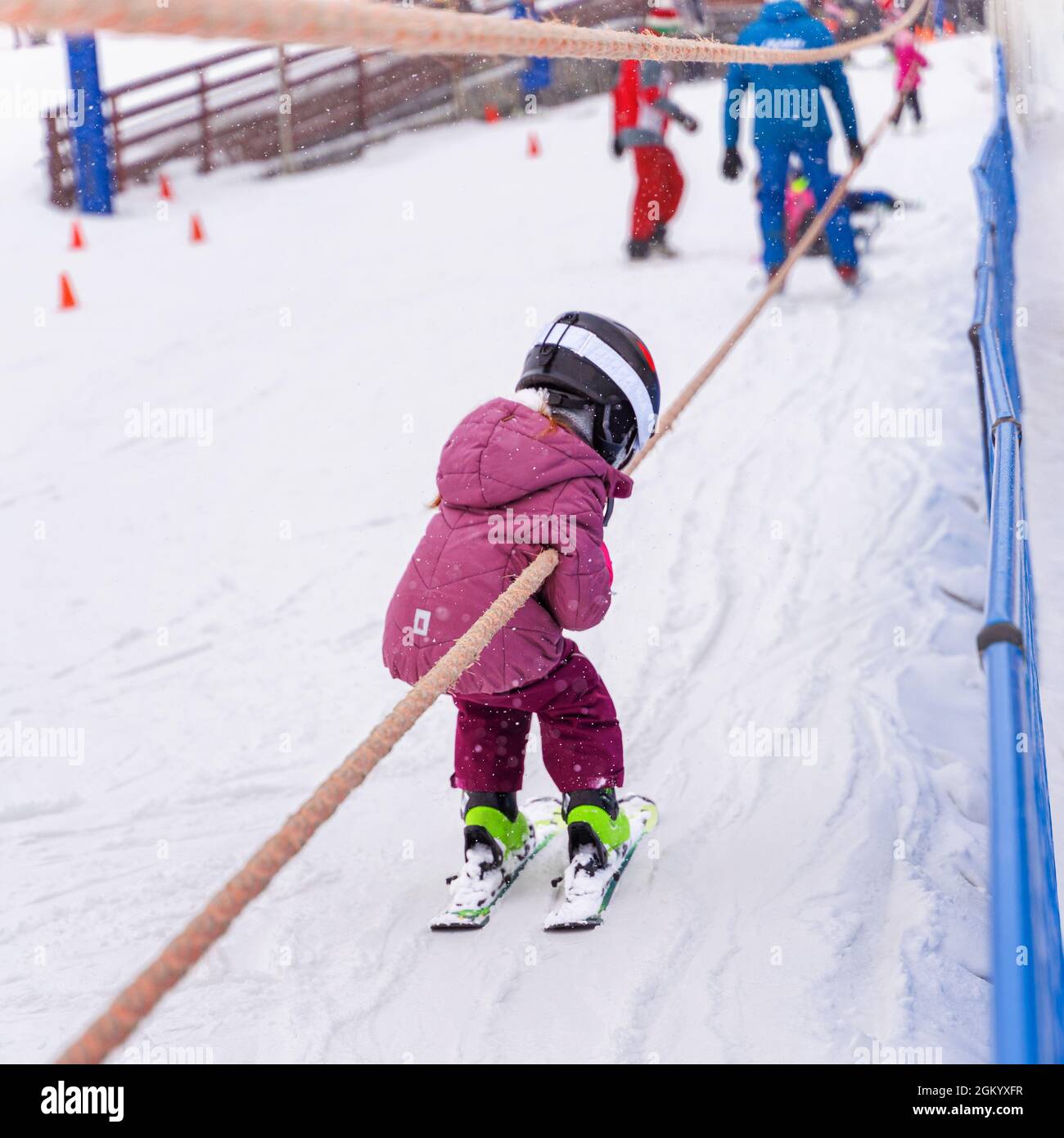 Pista da sci. Bambino in sci salendo in pista con baby lift in superficie.  Tempo libero invernale, stile di vita sportivo, allenamento sugli sci e  holi per famiglie all'aperto Foto stock -