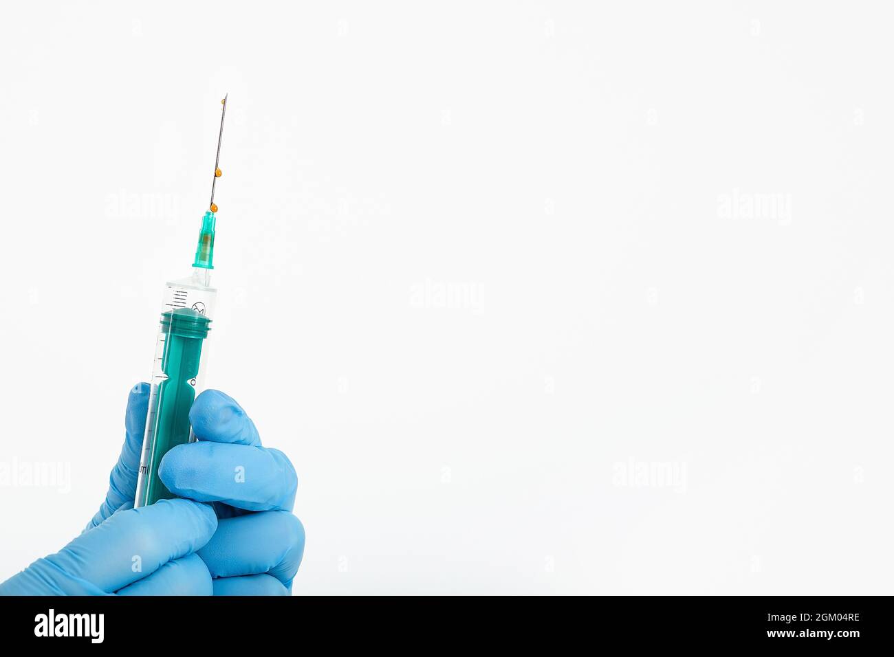 Una mano del medico in un guanto medico contiene una siringa con un ago per proteggere contro il virus dell'influenza. Vaccino CVD. Il concetto di vaccinazione medica Foto Stock