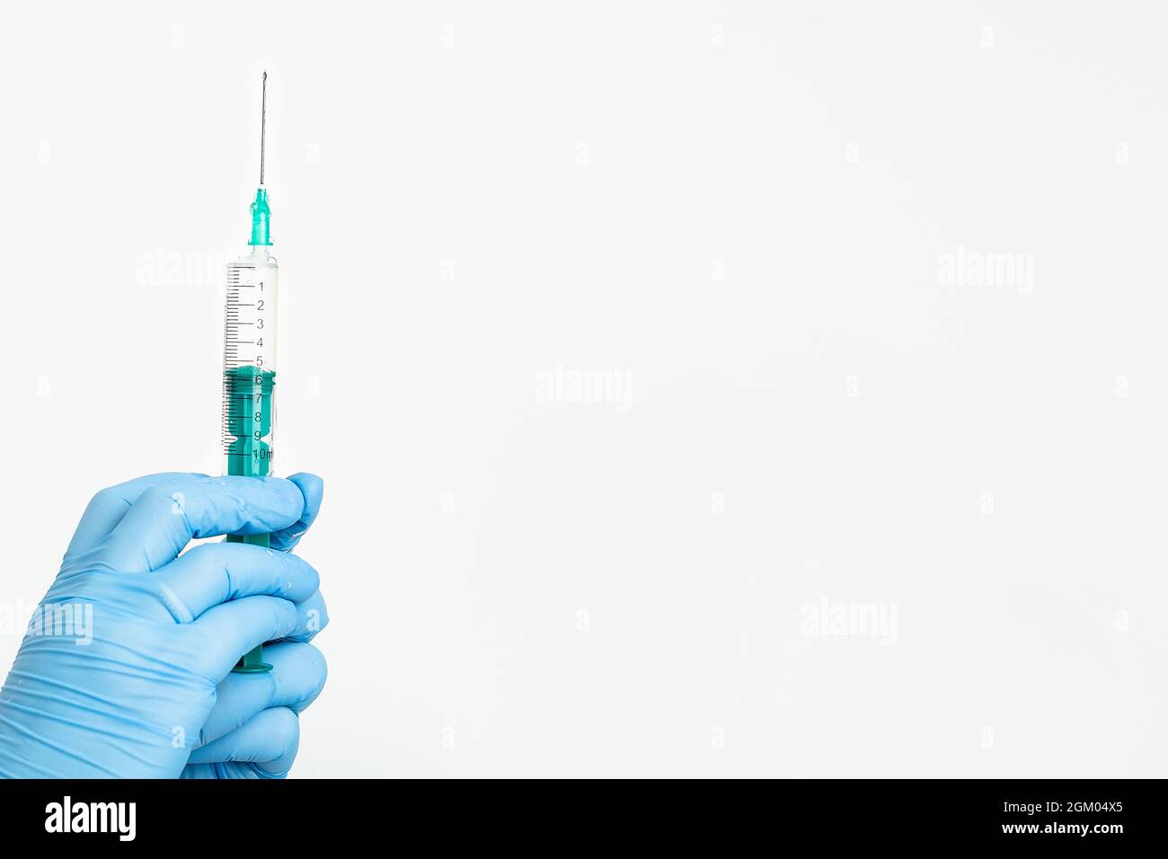 Una mano del medico in un guanto medico contiene una siringa con un ago per proteggere contro il virus dell'influenza. Vaccino CVD. Il concetto di vaccinazione medica Foto Stock