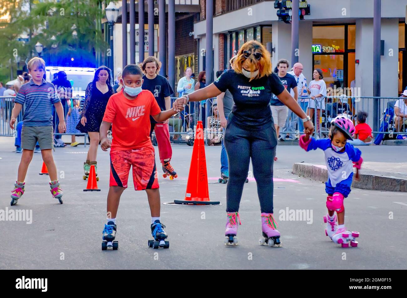 Una donna aiuta due bambini ad imparare a pattinare durante Roll Mobile, 10 settembre 2021, a Mobile, Alabama. La notte di skate si svolge mensilmente. Foto Stock
