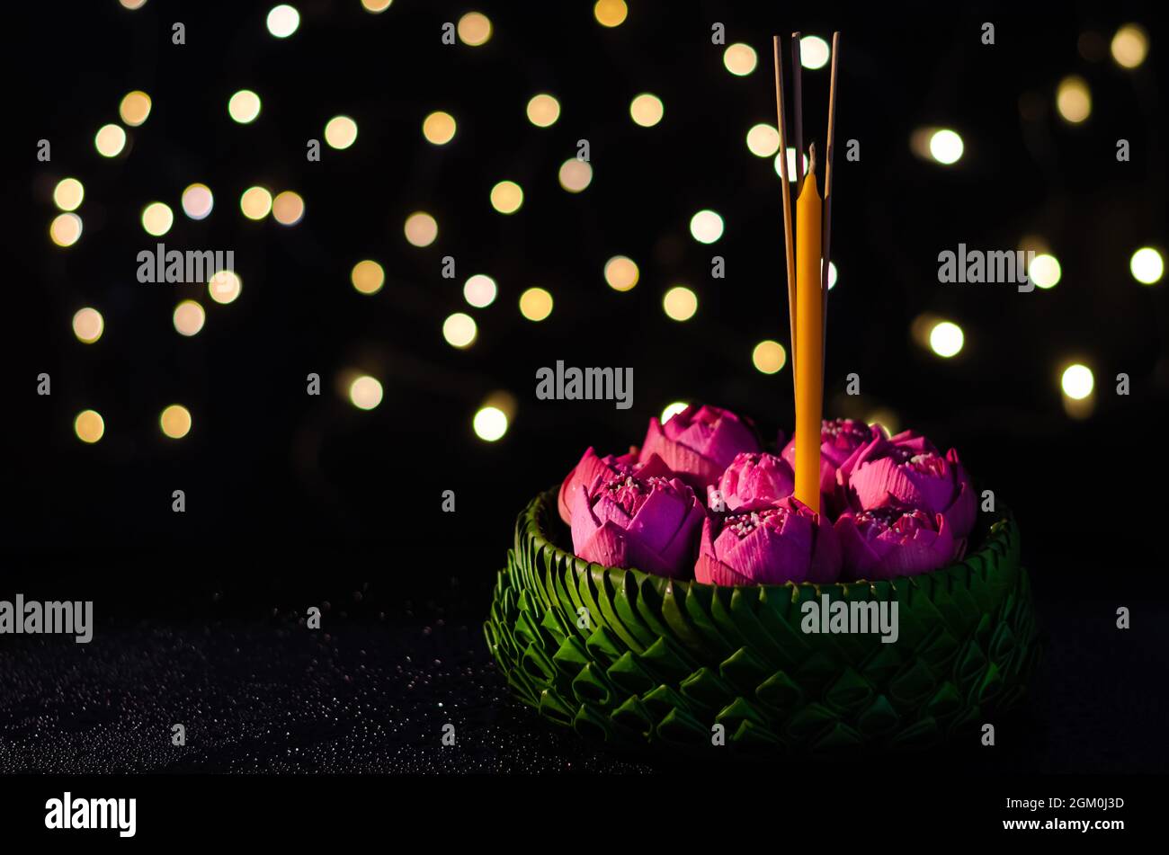 Fuoco selettivo sul fiore rosa del loto decora sulle foglie della banana Krathong con le luci di bokeh sfondo per la luna piena della Thailandia o festival del krathong di Loy. Foto Stock