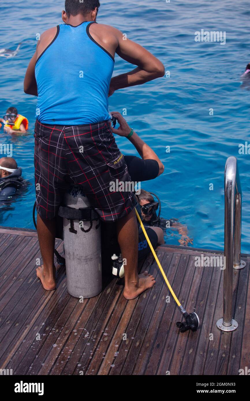 l'istruttore aiuta il turista a mettere su una tuta subacquea. verticale Foto Stock