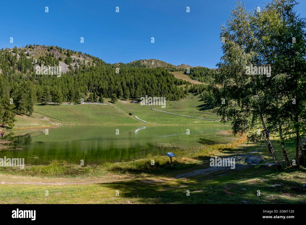 La natura circostante si riflette nelle acque del lago di Lod, Valle d'Aosta, Italia, nella stagione estiva Foto Stock