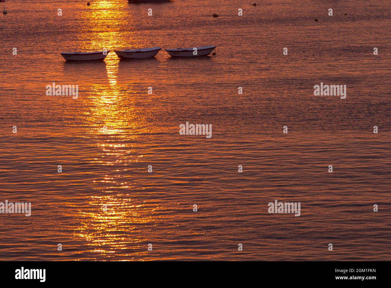 Tramonto rossastro sul mare calmo e calmo con barche da pesca in controluce. Silhouette di piccole barche al tramonto. Foto Stock