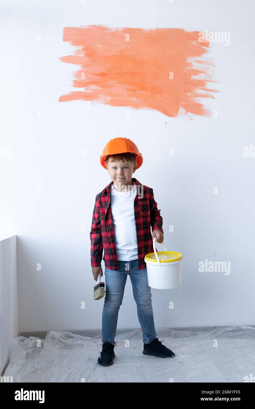 Ragazzo carino spazzolando le pareti. Concetto di ristrutturazione della casa. Il figlio aiuta i genitori a dipingere il muro. Piccolo aiutante. Foto Stock