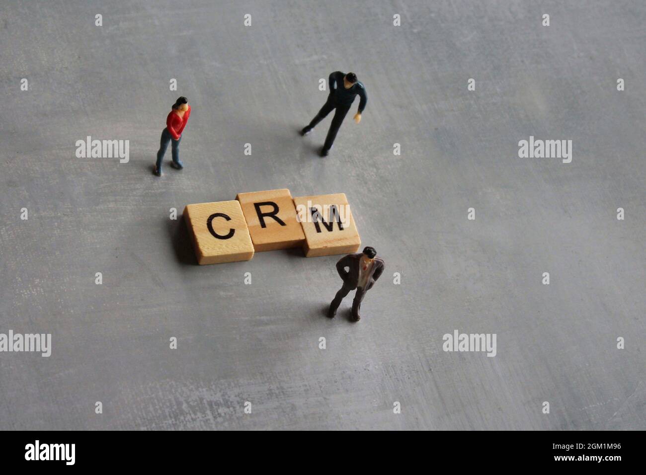 Concetto aziendale. Persone in miniatura e cubo di legno con CRM di testo o gestione delle relazioni con i clienti Foto Stock