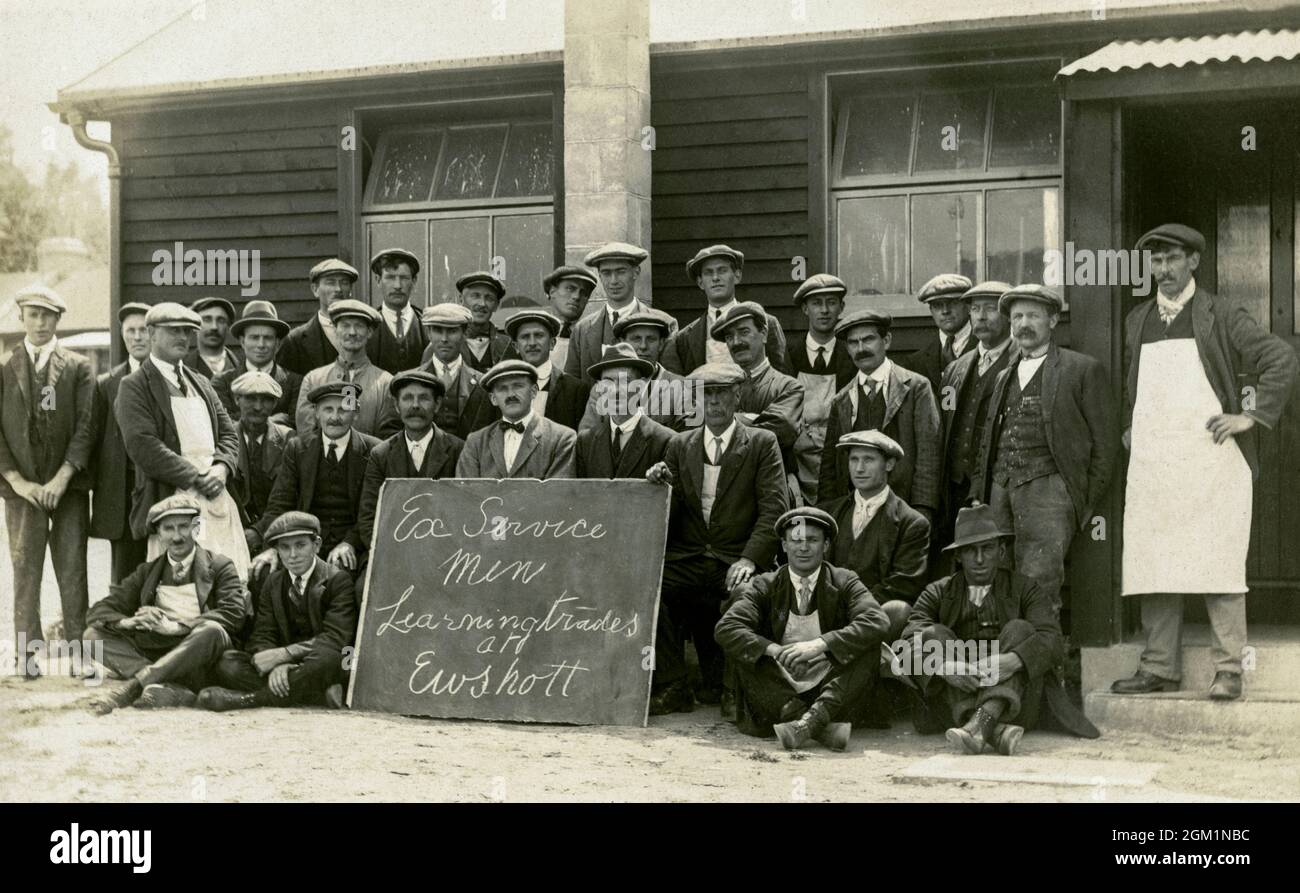 Ex soldati britannici della prima guerra mondiale in berretti piatti, imparando nuove abilità e mestieri dopo la guerra, posa con i loro istruttori (uno con un papillon) per una fotografia di gruppo formale a Ewshott Camp, vicino Fleet, Hampshire, Inghilterra. Foto Stock