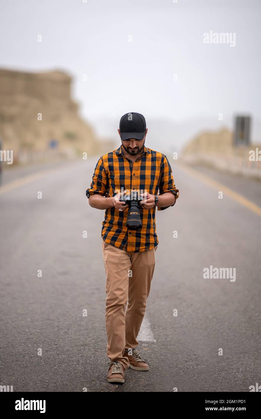 Uomo premuroso che tiene la macchina fotografica, fotografo cammina all'aperto con la sua macchina fotografica Foto Stock