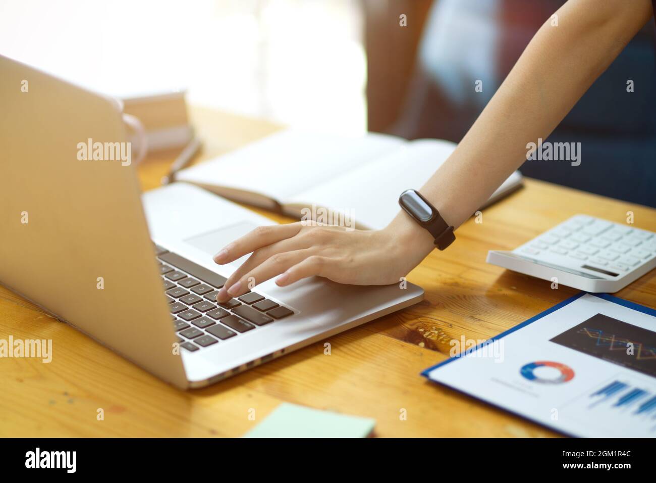 Foto ritagliata di una donna d'affari che digita dati finanziari su un computer portatile mentre si trova in ufficio. Dati finanziari grafici report e calcolatrice sul lavoro Foto Stock