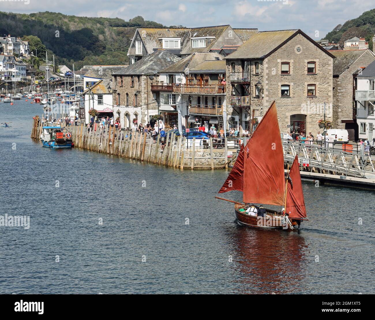 L'iconica tela rossa naviga su una barca che percorre il River Looe in Cornovaglia con un'affollata banchina a East Looe come sfondo. Looe Cornovaglia. Foto Stock
