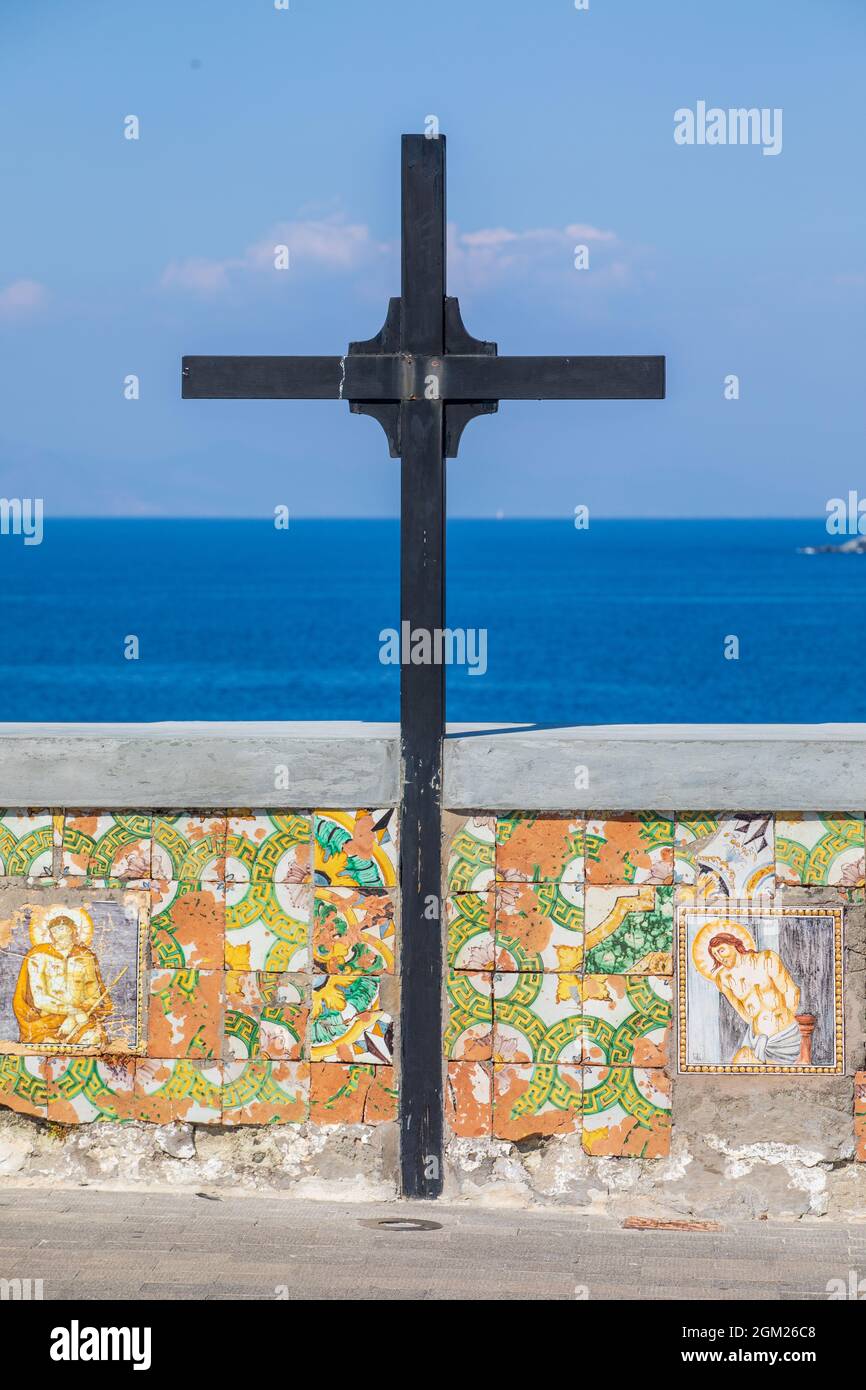 Croce di legno con una parete bassa decorata con icone religiose che si affacciano sul mare. Ubicazione: Forio, Chiesa del Soccorso Foto Stock