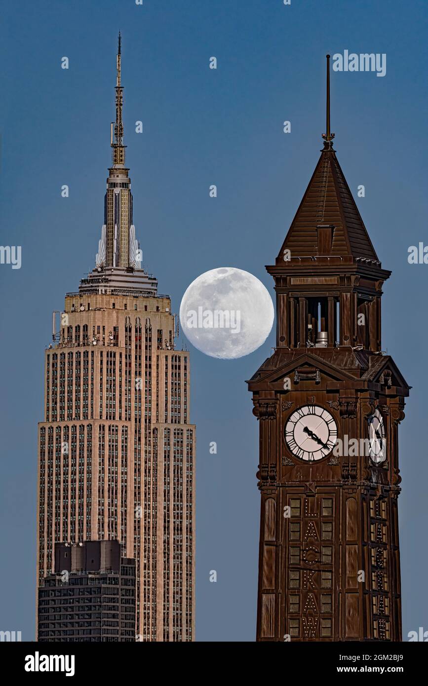 NJ NYC Crossing state Lines - l'intera Luna di neve sorge tra la Torre dell'Orologio di Lackawanna a Hoboken, New Jersey e l'Empire state Building nel New Jersey Foto Stock