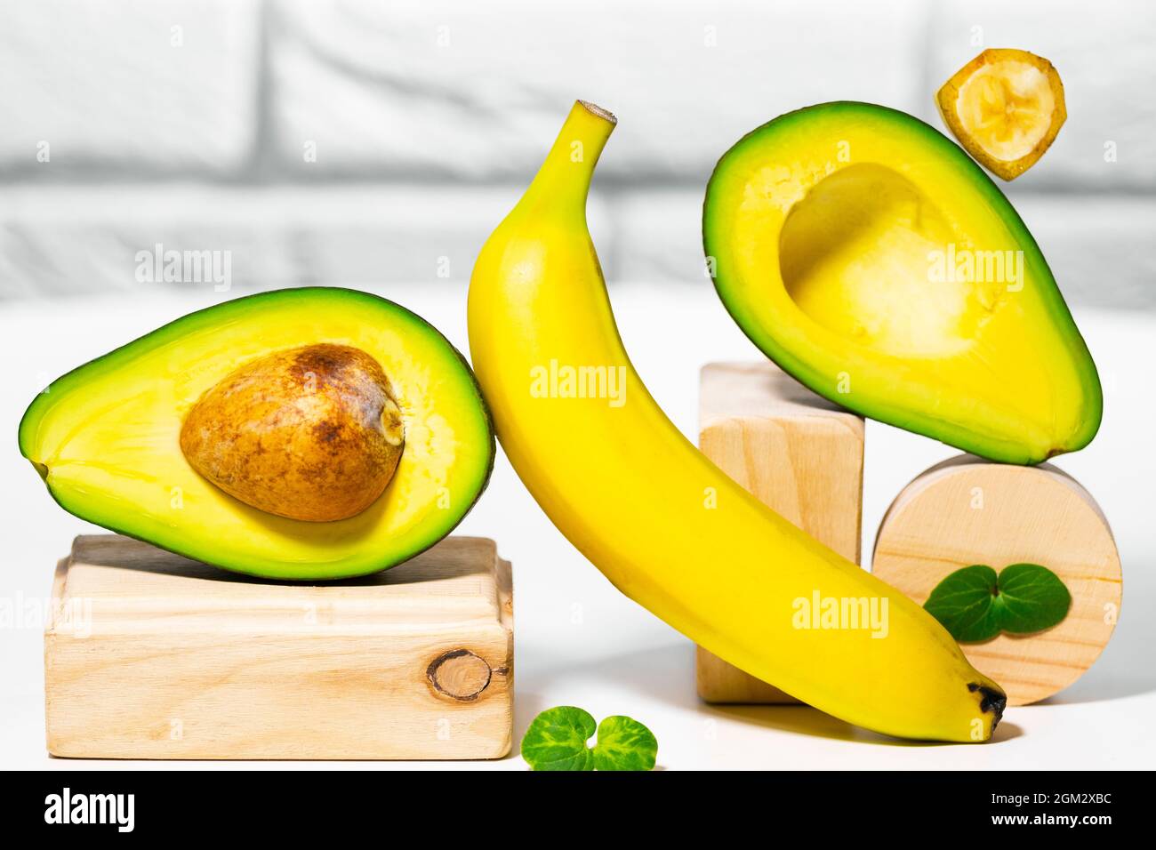 Avocado creativo, banana e micro verde equilibrio legno stand e podi., sfondo bianco, equilibrio sano cibo. Concetto di nutrizione equilibrata Foto Stock