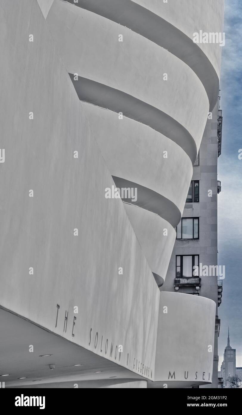 Guggenheim Museum and ESB - lo stile architettonico moderno del Guggenheim Museum con una piccola vista sull'antenna dell'Empire state Building nel bac Foto Stock