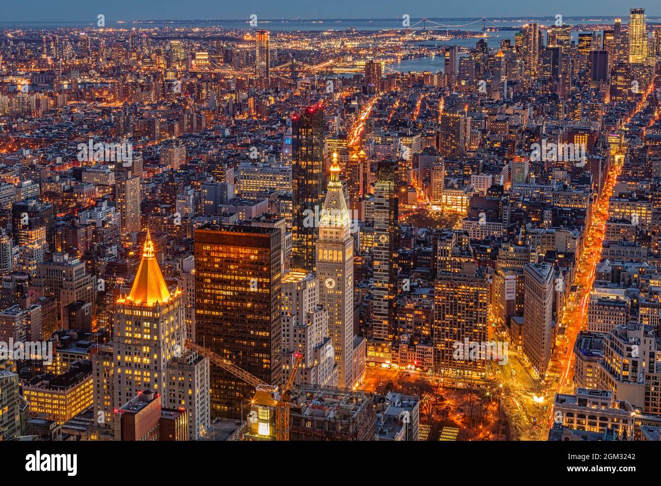 Urban New York City Aerial - Vista dall'alto allo skyline illuminato di Manhattan con il suo edificio e distributore Flatiron, il ponte Verrazano Narrows Foto Stock