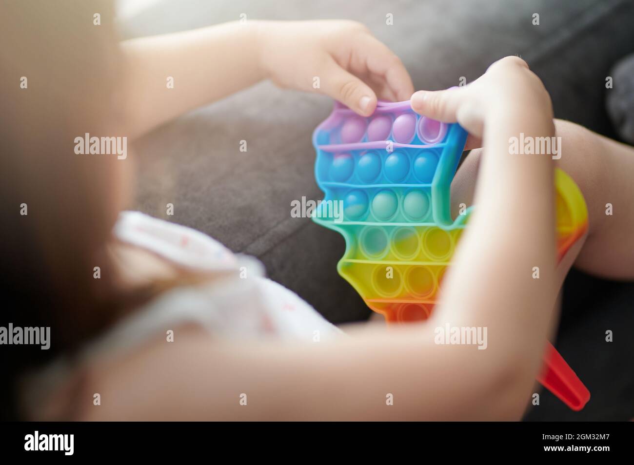 Bambina. Gioca con il giocattolo popit in plastica in background casa Foto Stock
