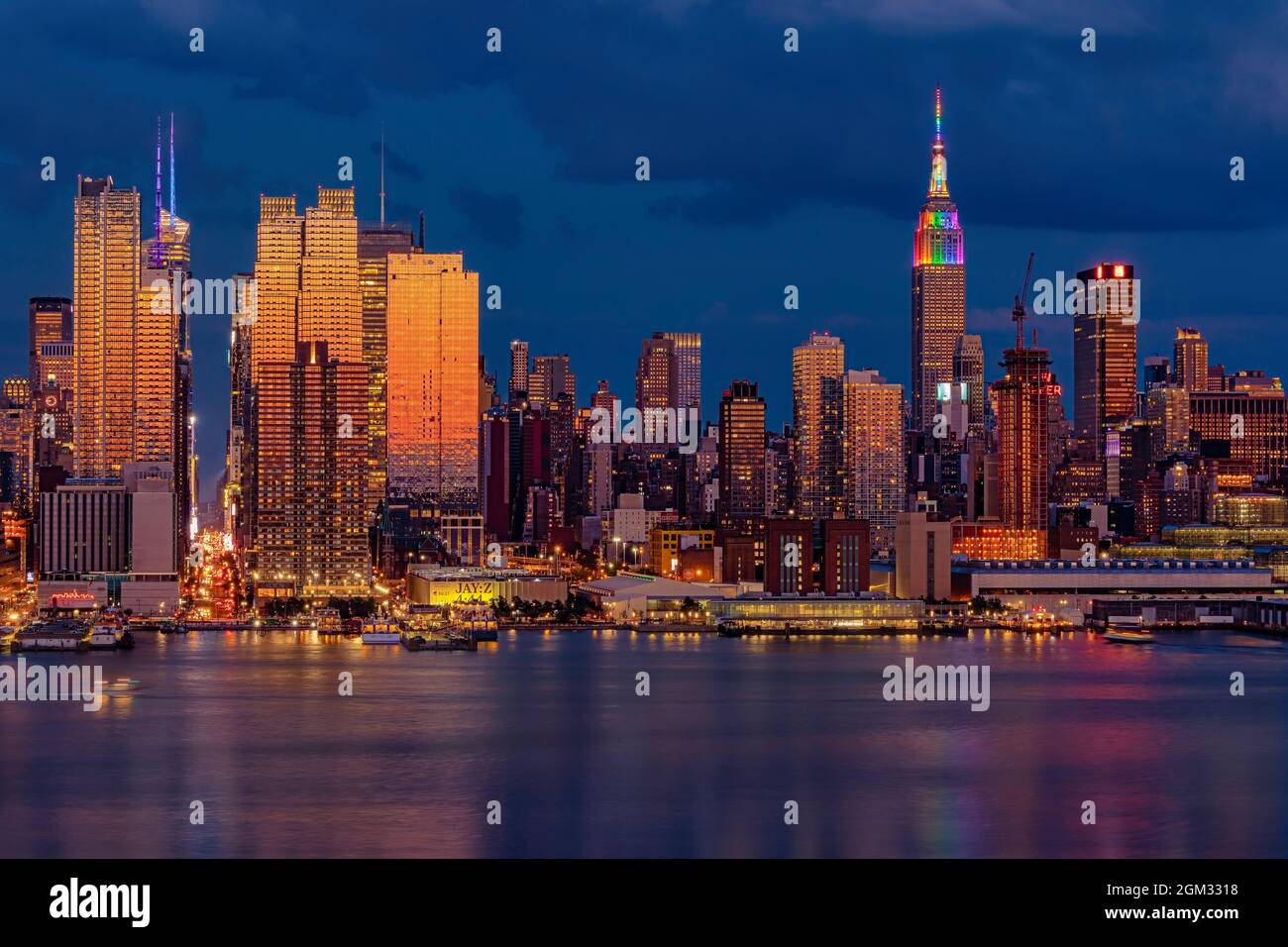 La città di New York skyline orgoglio - Il midtown Manhattan NYC skyline è bagnata con calde e fredde tonalità di colore durante le ore di colore blu al crepuscolo. L'Empire State Foto Stock