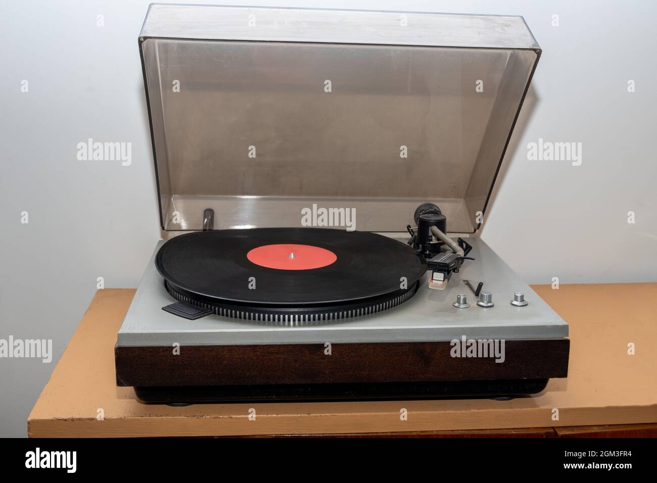 Giradischi stereo analogico retro vintage su un tavolo in legno. Un giradischi in plastica vecchio stile che riproduce una traccia musicale, vista frontale. Concetto di musica retrò Foto Stock