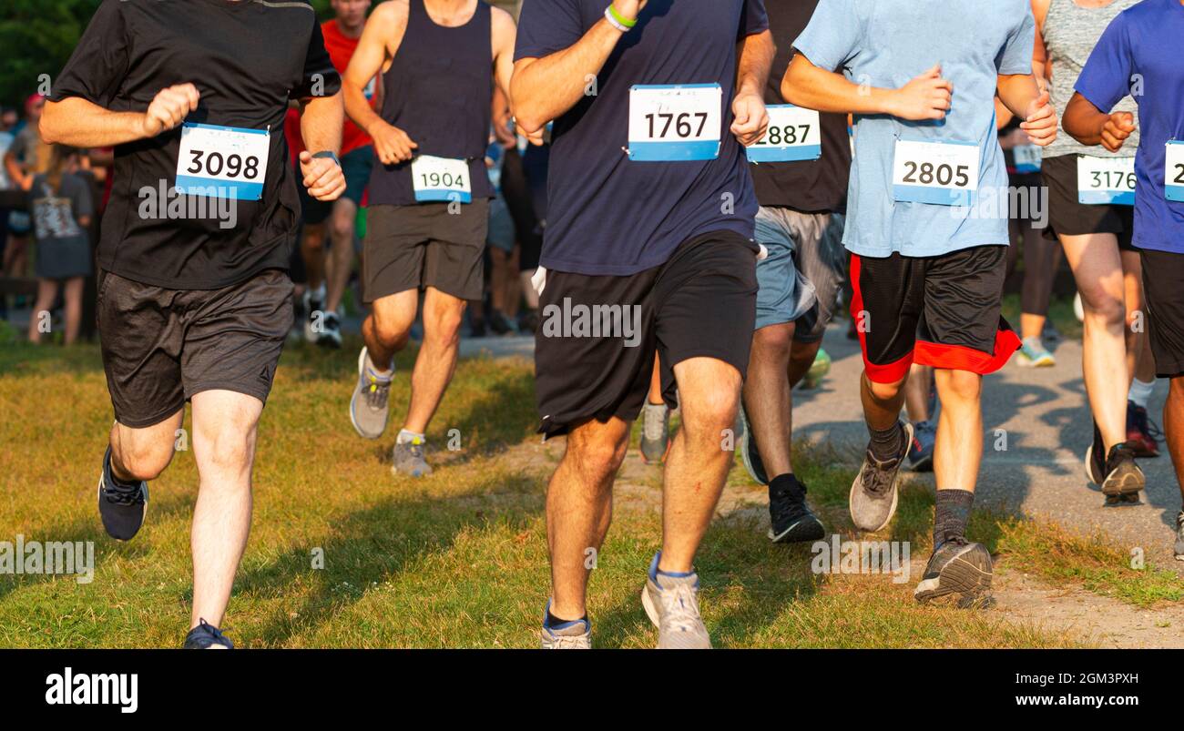Corridori che corrono una corsa 5K sull'erba dentro durante un evento molto affollato. Foto Stock