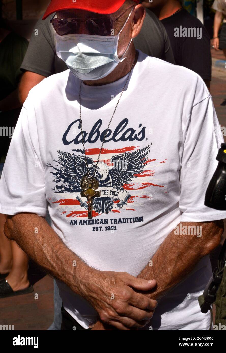 Un uomo indossa una T-shirt, un Crocifisso e una maschera per il viso di Cabela a Santa Fe, New Mexico. La catena di negozi sportivi ha sede a Sidney, Nebraska. Foto Stock