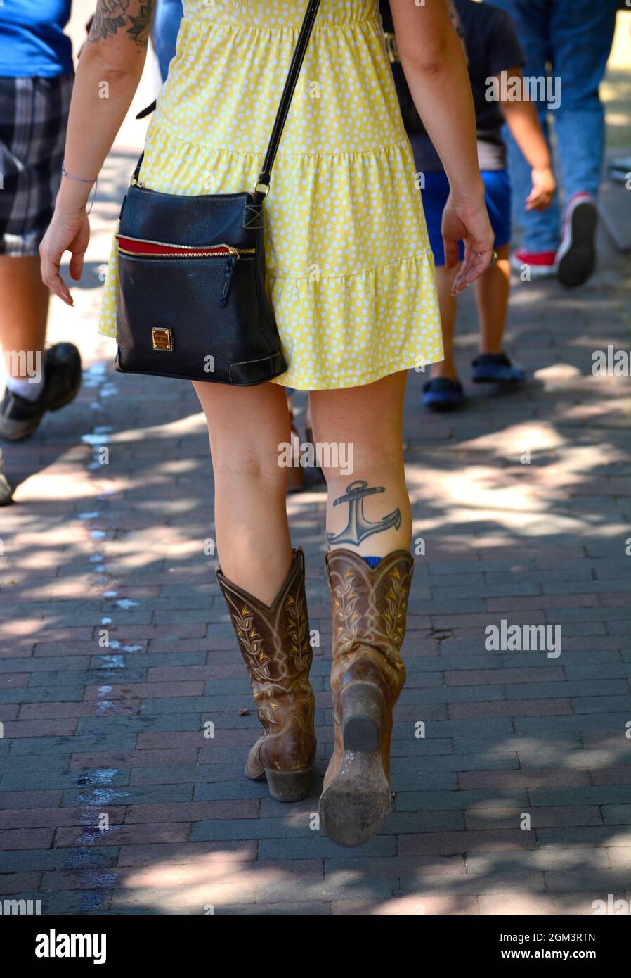 Una donna con un tatuaggio dell'ancora di una nave sul suo vitello cammina lungo un marciapiede a Santa Fe, New Mexico. Foto Stock