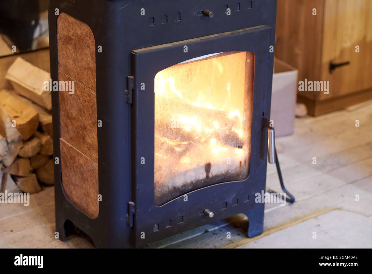 Stufa a legna di design moderno. Porta della camera antincendio con vetro termoresistente attraverso il quale è possibile vedere la fiamma. Foto Stock