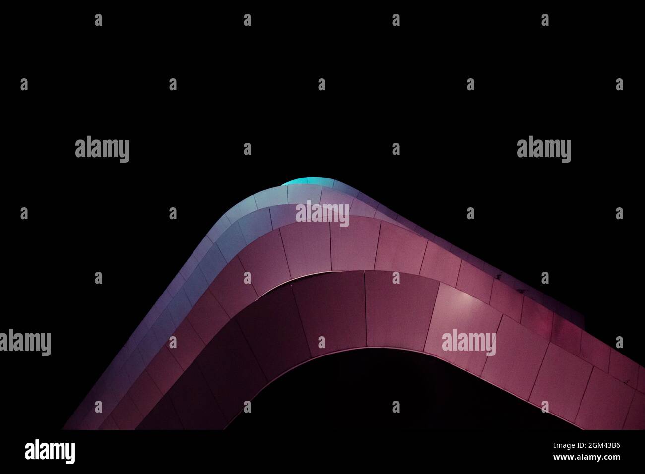 Edificio curvo dall'architettura moderna con luci a LED di notte dal basso Foto Stock