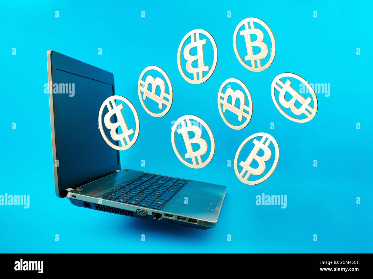 Monete d'oro Bitcoin che volano fuori dal portatile su sfondo blu. Concetto di rete aziendale di estrazione Bitcoin e simbolo di criptovaluta virtuale. 3D illust Foto Stock
