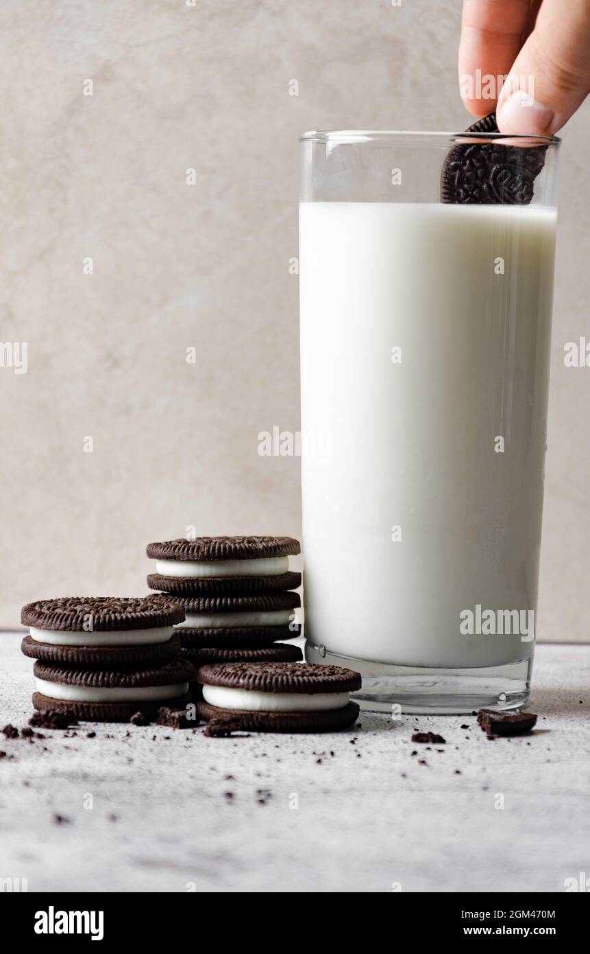 Immergere i biscotti Oreo in un bicchiere di latte Foto Stock