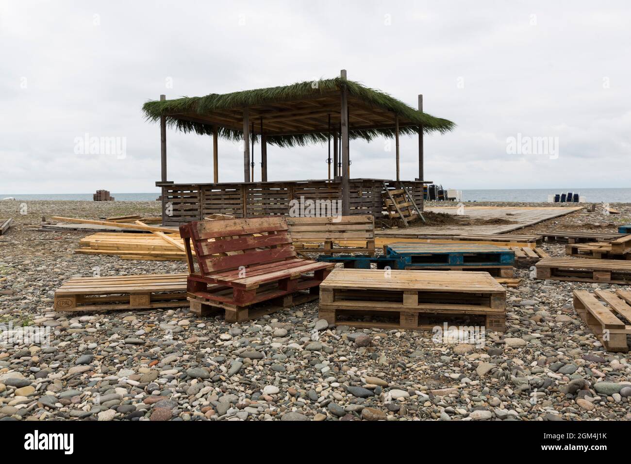 Costruzione del padiglione sulla spiaggia. Spiaggia di ciottoli e Mar Nero Batumi. Materiali da costruzione, pallet. Foto Stock