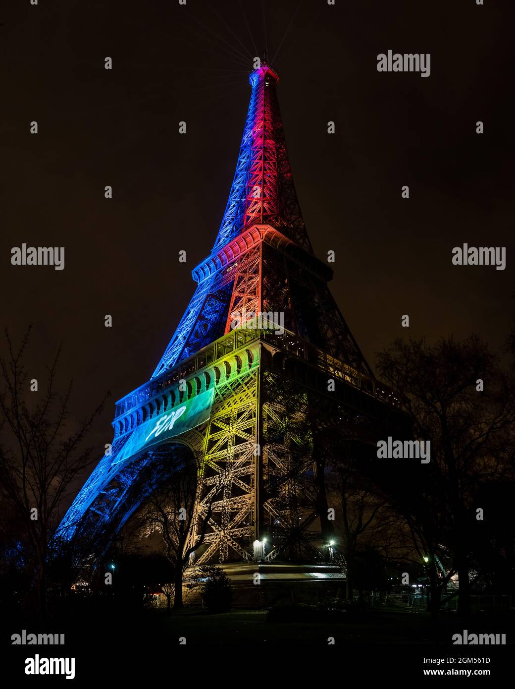 Vista alta verticale della Torre Eiffel illuminata di notte dai colori dell'arcobaleno. Creato per la condivisione Foto Stock