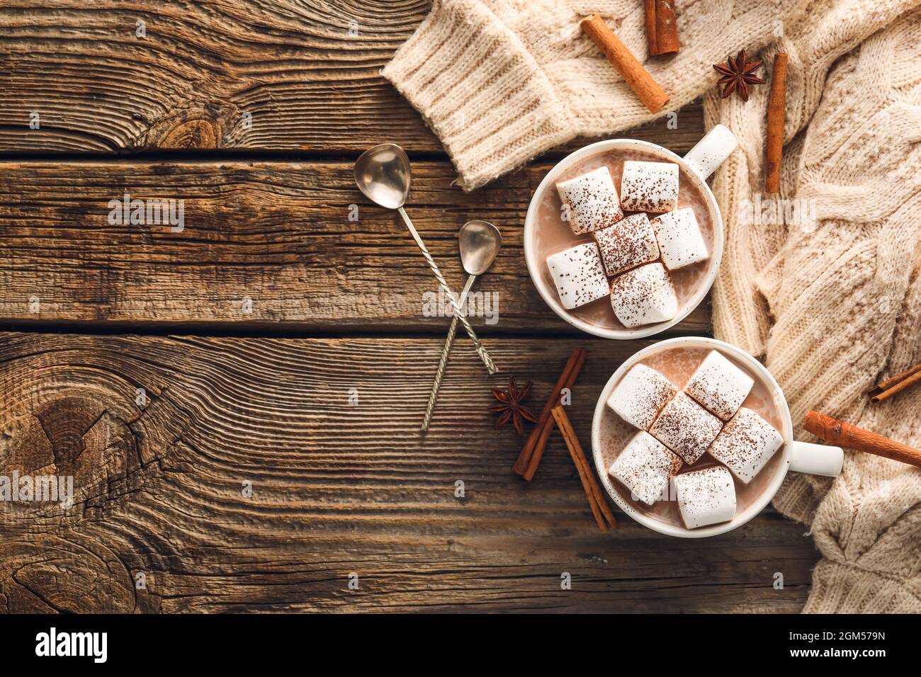 Composizione con tazze di cioccolata calda, marshmallows e cannella su sfondo ligneo Foto Stock