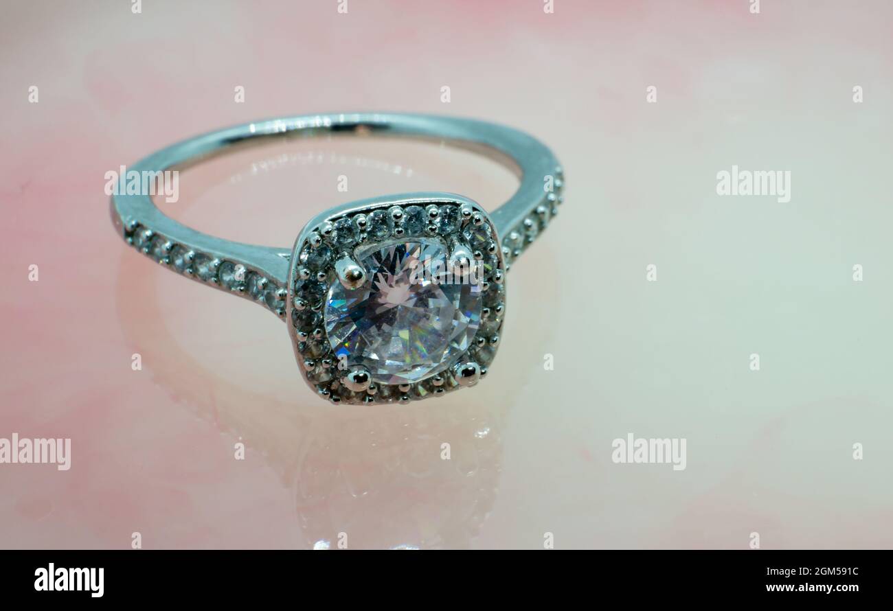 primo piano anello di nozze in diamante argento con foto su marmo rosa Foto Stock