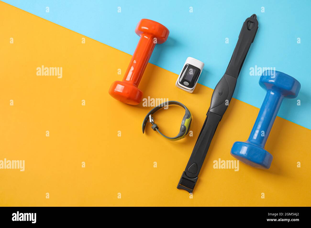 Pulsossimetro, manubri, fitness tracker e cintura toracica su sfondo colorato Foto Stock