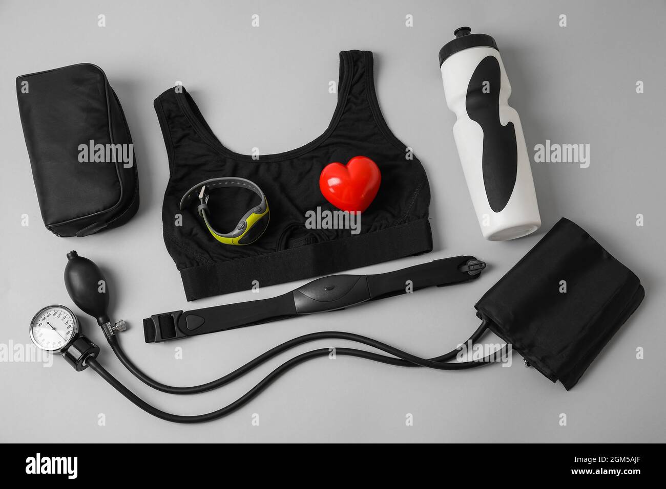 Composizione con sfigmomanometro, tracker fitness e cintura toracica su sfondo grigio Foto Stock