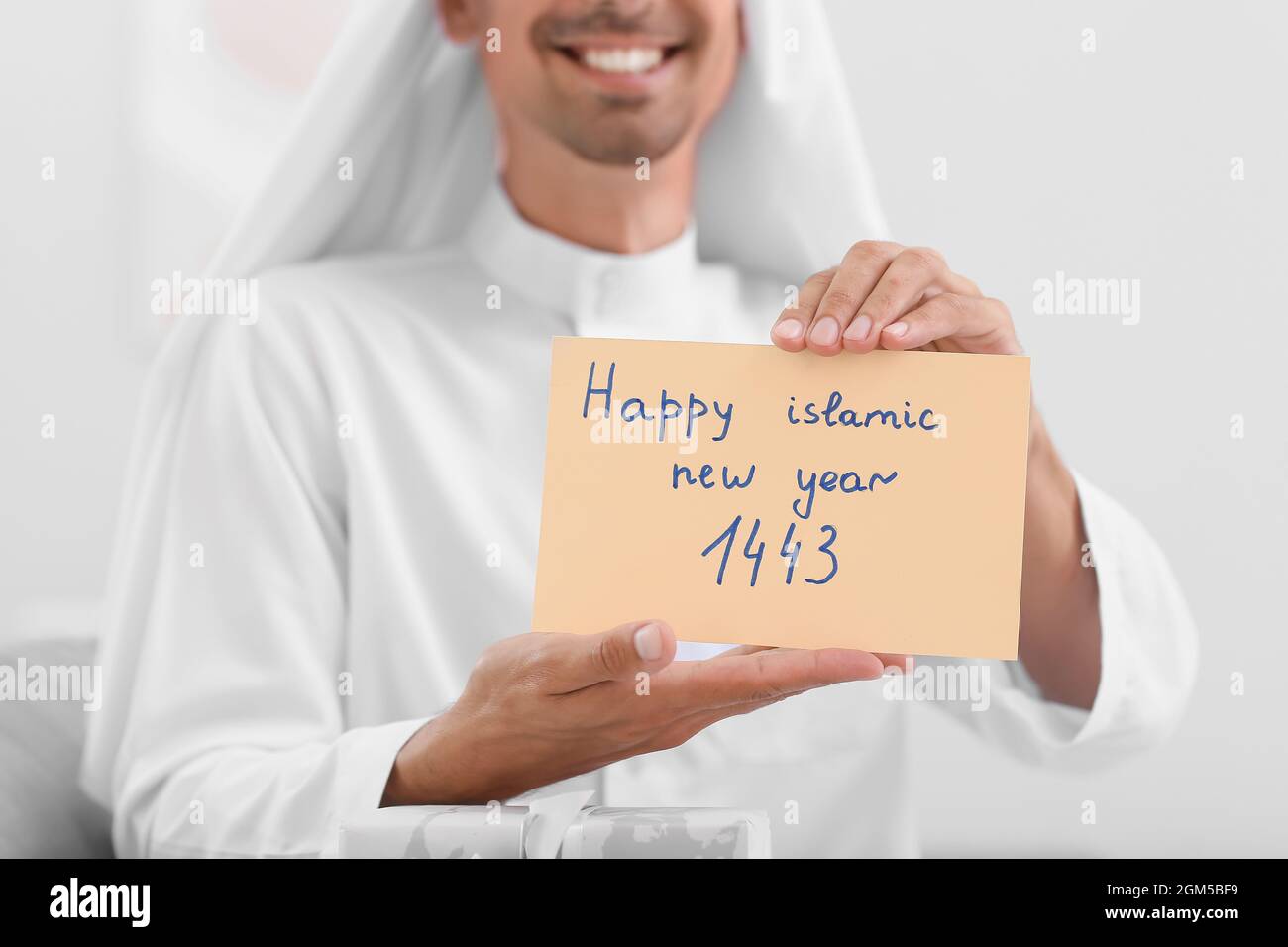 Giovane musulmano con biglietto d'auguri per il Capodanno islamico a casa Foto Stock