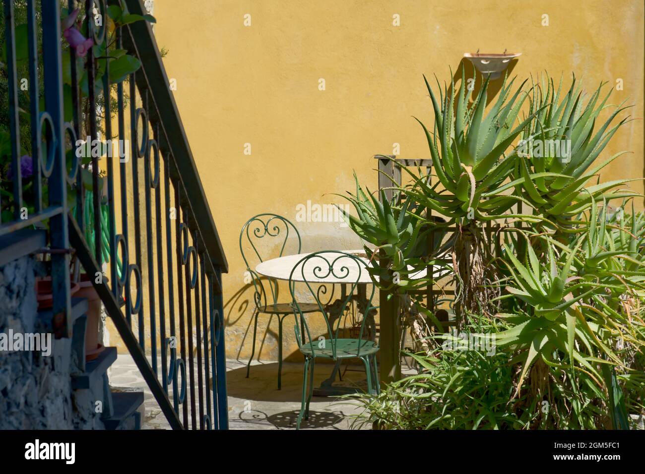 Un tavolo con sedie in un patio adornato di agave in una tipica casa colonica sulle coste del Mediterraneo Foto Stock