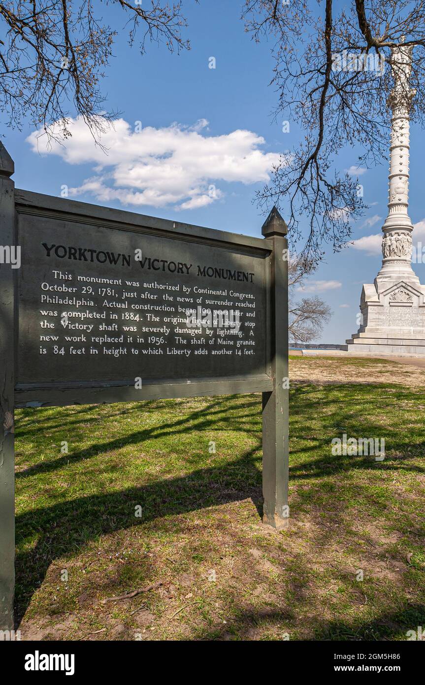 USA, Virginia, Yorktown - 30 marzo 2013: Ritratto, Monumento alla Vittoria di White Yorktown in combinazione con la scheda spiegazione posta su agai verde-marrone collina Foto Stock
