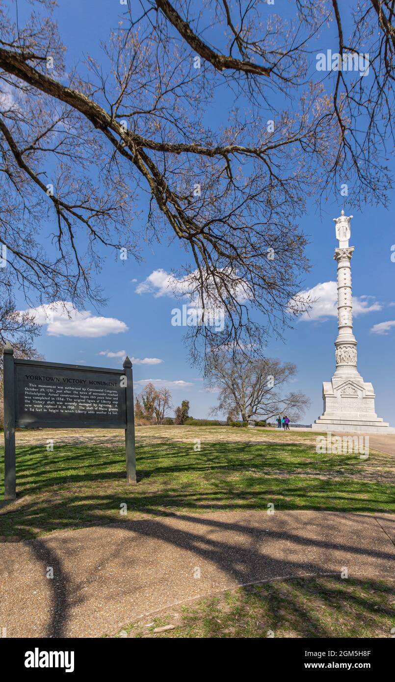 USA, Virginia, Yorktown - 30 marzo 2013: White Yorktown Victory Monument in combinazione con la bacheca delle spiegazioni posta su una collina verde-marrone contro il blu c Foto Stock