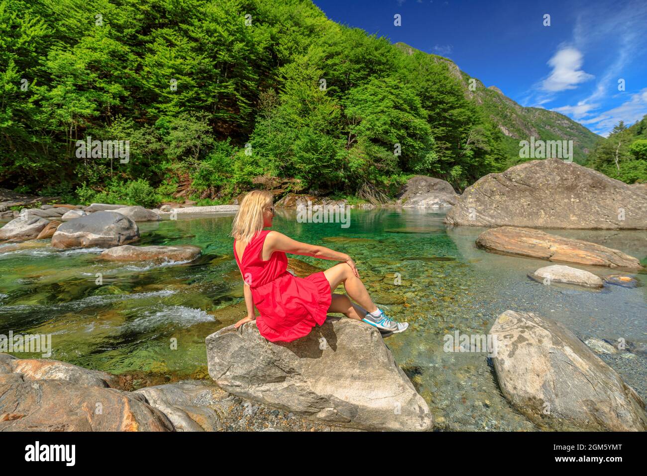 La donna si rilassa sulle rocce del fiume Verzasca. Valle Verzasca per la città di Lavertezzo. Famoso punto di riferimento per lo svago lungo il fiume e le immersioni in Ticino Foto Stock