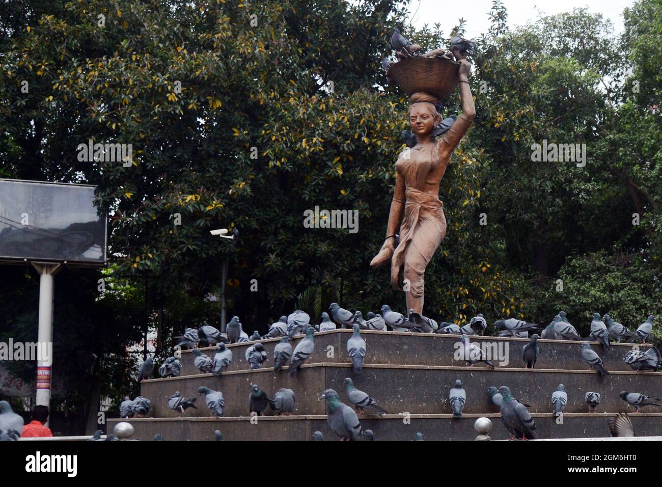 Una scultura di una donna che porta un cestino sulla sua testa in una rotonda a Pune, India. Foto Stock