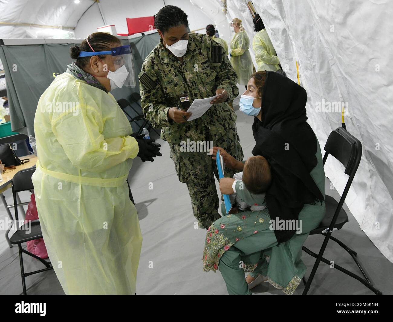 Personale medico della Marina degli Stati Uniti e volontari delle ONG aiutano una famiglia afghana con la pre-selezione alla stazione medica del villaggio della libertà della Task Force, la base comune McGuire-Dix-Lakehurst, New Jersey, 11 settembre 2021. Il Dipartimento della Difesa, attraverso il comando del Nord degli Stati Uniti, e a sostegno del Dipartimento della sicurezza interna, sta fornendo trasporto, alloggio temporaneo, screening medico, e supporto generale per almeno 50,000 sfollati afghani in strutture adeguate, in strutture permanenti o temporanee, il più rapidamente possibile. Questa iniziativa fornisce al personale afghano un sostegno essenziale in luoghi sicuri Foto Stock