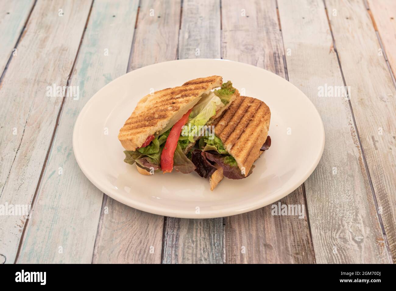 Panino vegano con peperoni e lattuga all'interno del pane affettato con i segni di tostatura alla griglia Foto Stock