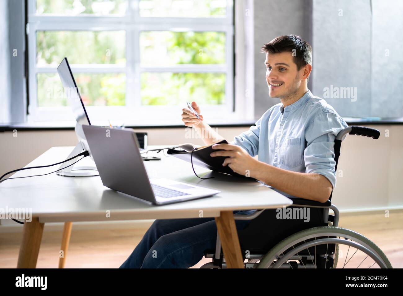 Assistente virtuale disabilitato in sedia a rotelle effettua videochiamata remota Foto Stock